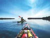 Two kayaks are seen paddling on Lake Huron on a clear day with blue skies and calm water.